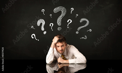 Sitting businessman under question marks photo