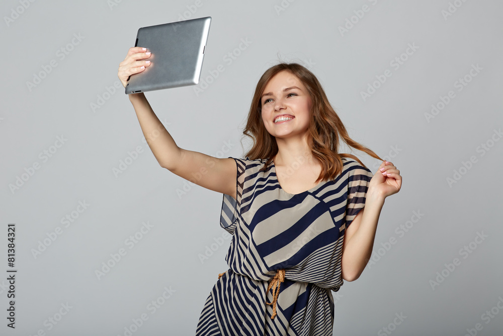 Young woman taking selfie with digital tablet, on gray backgroun Young woman taking selfie with digital tablet, on gray backgroun