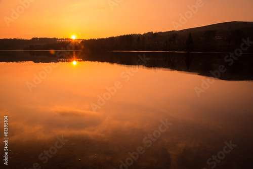 colorful and relaxing sunset over calm lake with reflection in w