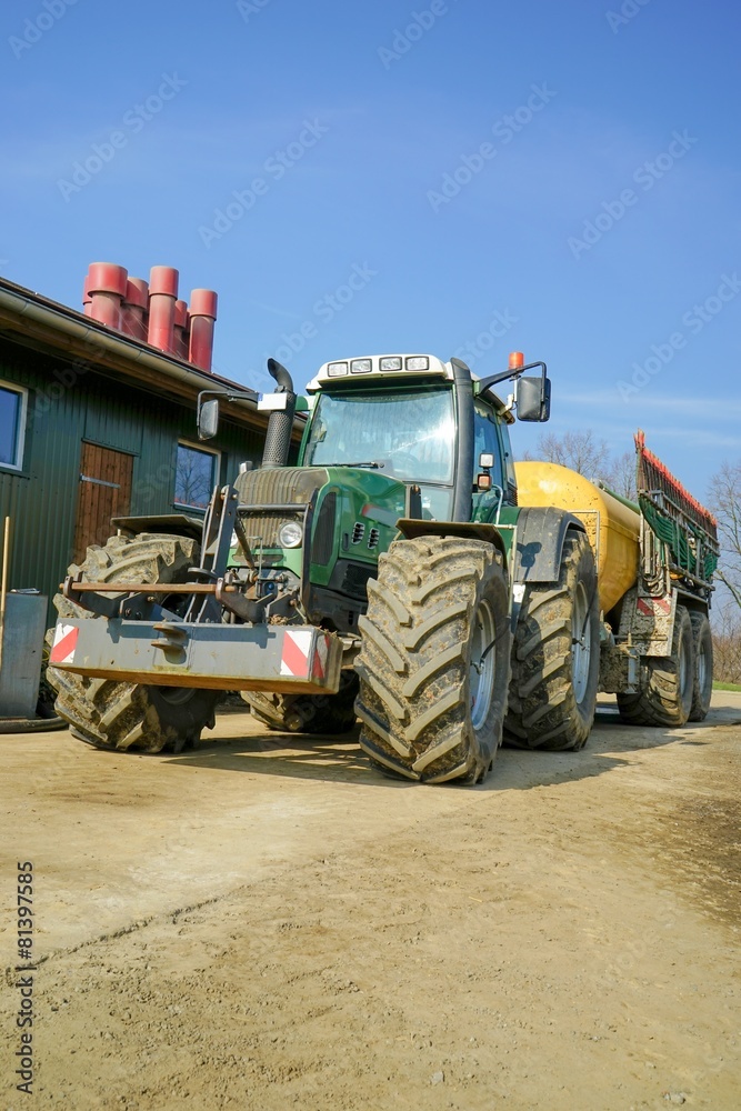 Am Maststall abgestellter Schlepper mit Güllefass, Hochformat Am Maststall abgestellter Schlepper mit Güllefass, Hochformat