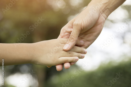 Mother holding a hand of his son in summer day