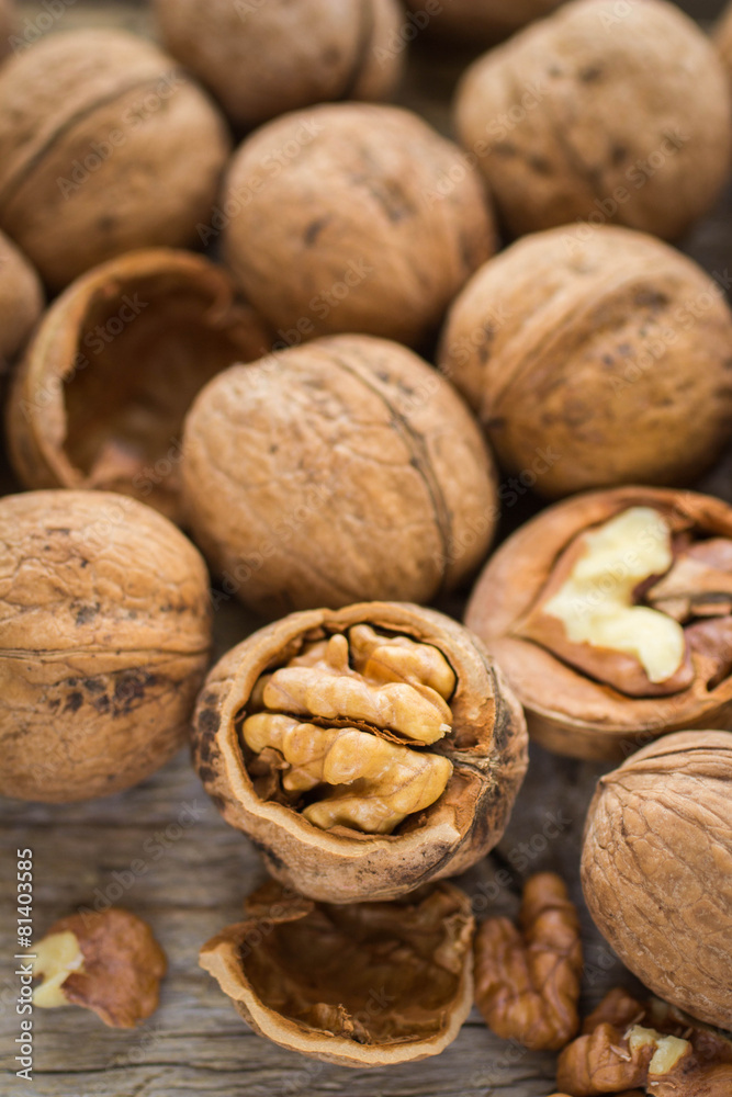 Walnut kernels and whole walnuts on rustic old wooden table