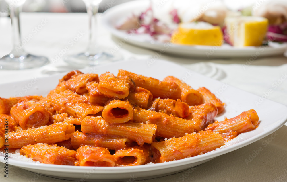 Piatto di rigatoni all'amatriciana su tavola apparecchiata Piatto di rigatoni all'amatriciana su tavola apparecchiata