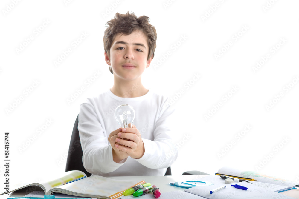 Caucasian smooth-skinned boy holds a lightbulb while doing homew Caucasian smooth-skinned boy holds a lightbulb while doing homew