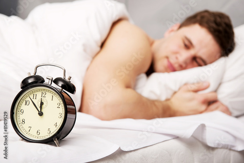 Man with alarm clock in bedroom. photo