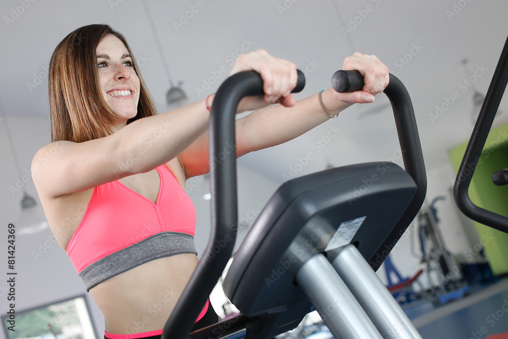 Young woman uses stationary bicycle trainer. Young woman uses stationary bicycle trainer.
