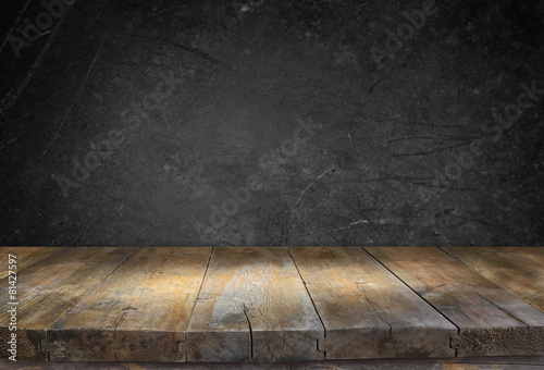 Grunge vintage wooden board table in front of black textured bac