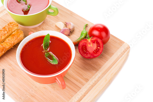 Bowl of tomato soup on wood platter.