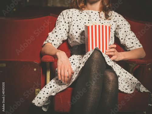 Young woman sitting in movie theater with popcorn