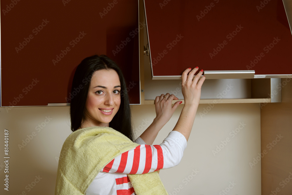 Housewife brunette in home clothes kitchen cupboard opens Housewife brunette in home clothes kitchen cupboard opens