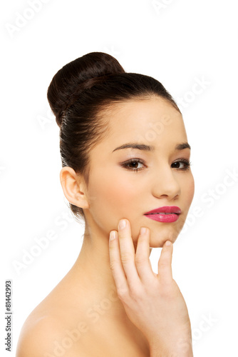 Woman with full make up touching face.