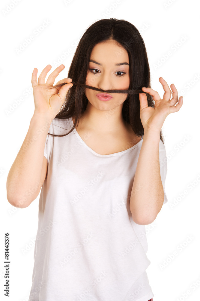 Teen woman putting hair like moustache. Teen woman putting hair like moustache.