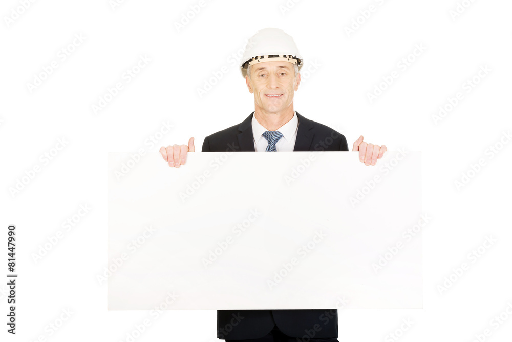 Businessman with hard hat holding empty banner Businessman with hard hat holding empty banner