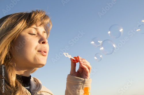 young girl blow bubbles against the blue sky