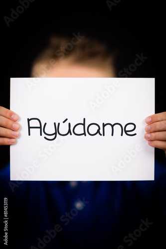 Child holding sign with Spanish word Ayudame - Help Me
