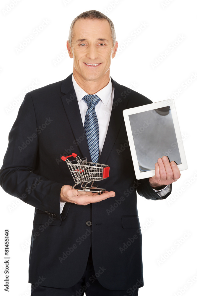 Businessman holding shopping cart and tablet Businessman holding shopping cart and tablet