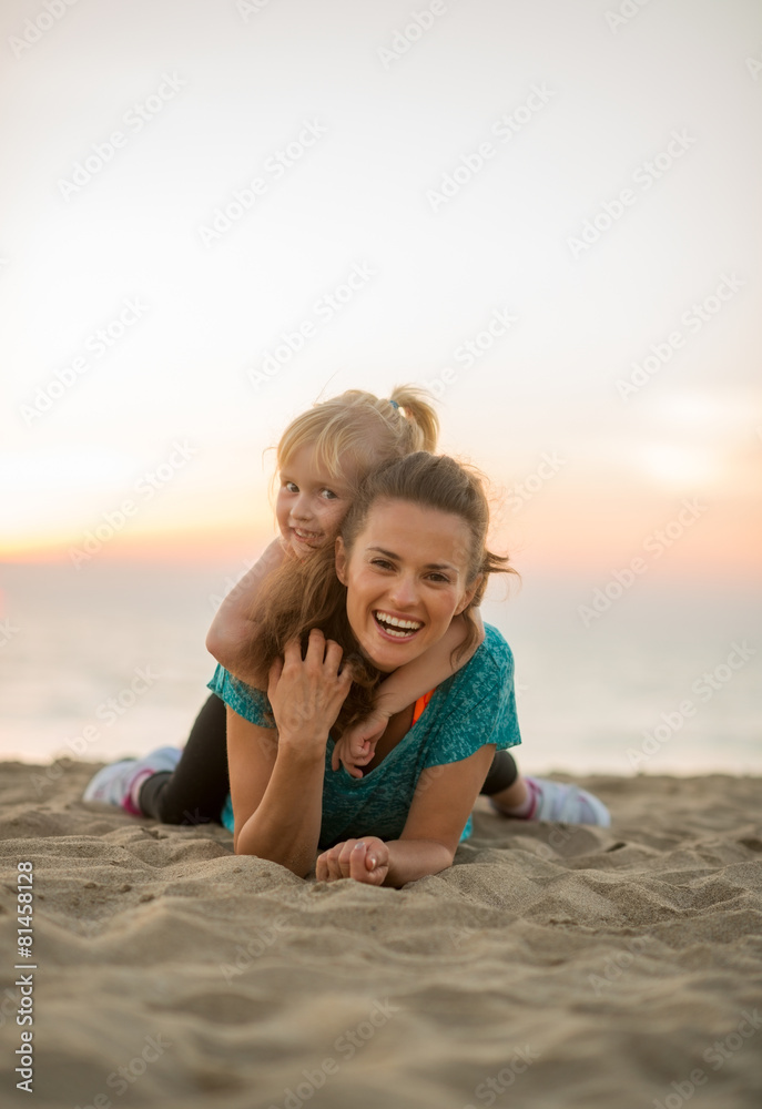 Happy mother and baby girl laying on beach in the evening Happy mother and baby girl laying on beach in the evening