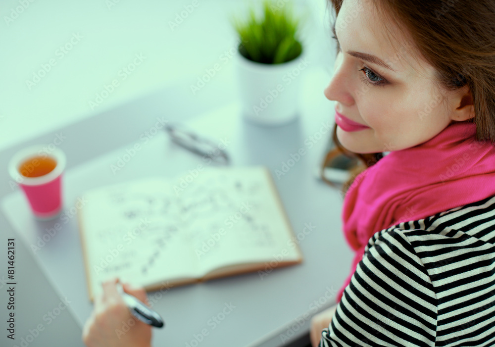 Young woman writes to diary on a white table Young woman writes to diary on a white table