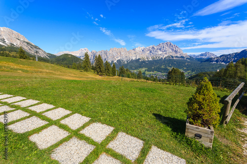Path on green grass in Dolomites Mountains, Italy