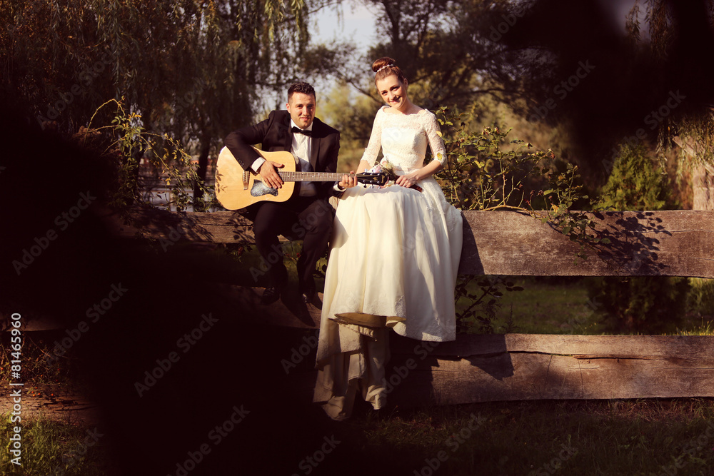 Fototapeta premium Groom playing on guitar for his bride