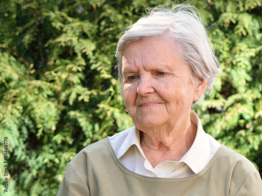 Senior woman smiling and dreaming in garden.
