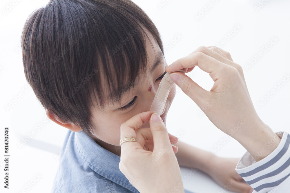 The doctor bandaids the forehead of the boy The doctor bandaids the forehead of the boy