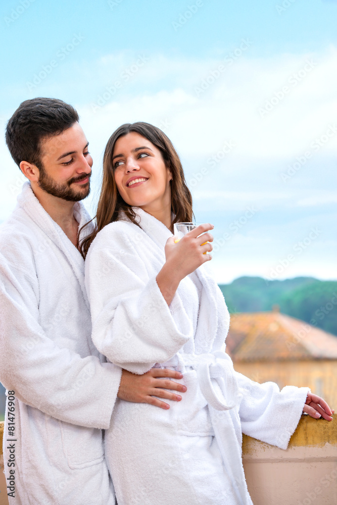 Obraz premium Couple in bathrobe standing on hotel balcony.