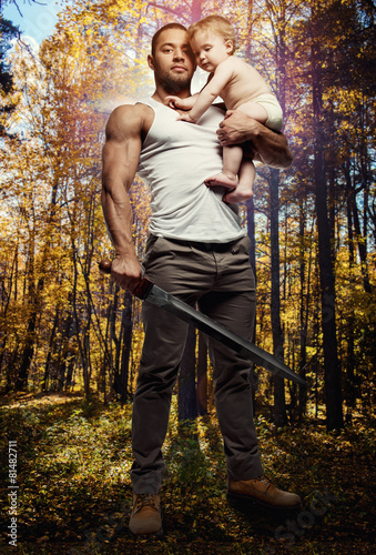 Father hugging a baby and holding a sword © Alex Tihonov