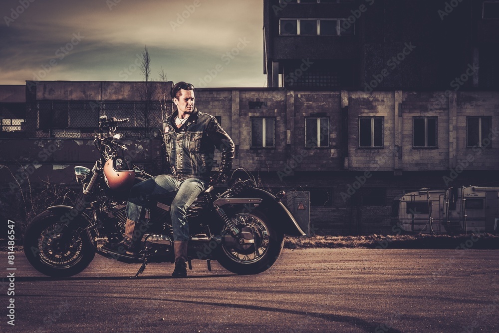 Biker and his bobber style motorcycle on a city streets Biker and his bobber style motorcycle on a city streets