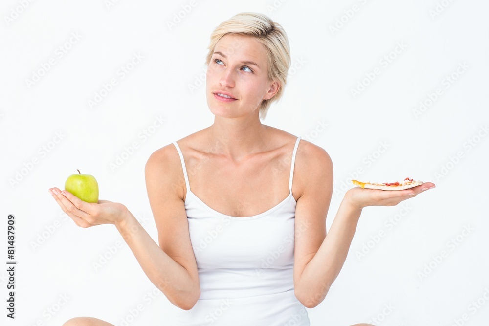 Pretty woman deciding between pizza and apple Pretty woman deciding between pizza and apple