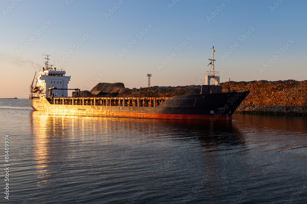 Freight ship in channel at sunset