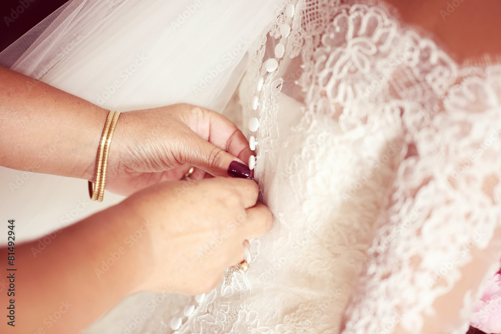 Fototapeta premium Hands helping the bride with wedding dress