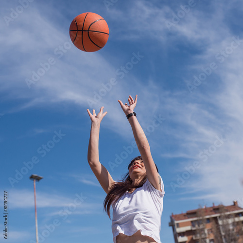 Young casual woman throwing basketball ball outdoors in a sunny © pio3