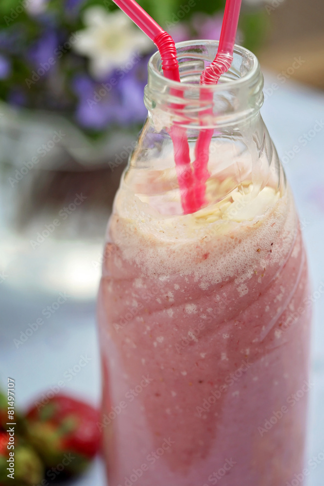 Strawberry smoothie freshly made in a jar with a lined straw Strawberry smoothie freshly made in a jar with a lined straw