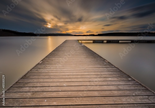 Fototapeta Naklejka Na Ścianę i Meble -  Beautiful long exposure lake with jetty at sunset.