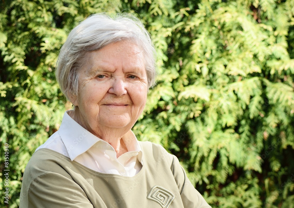 Senior woman smiling and dreaming in garden.