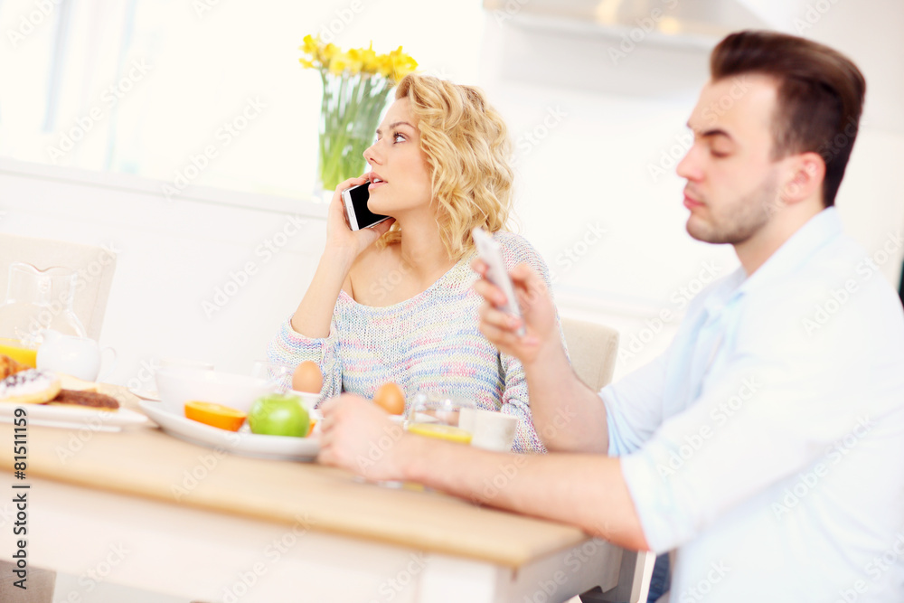 Happy couple eating breakfast and using smart phone Happy couple eating breakfast and using smart phone