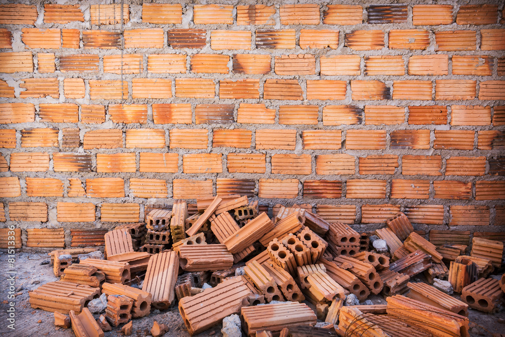 pile of bricks in construction site with brick wall background