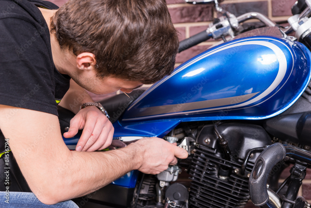 Young Guy Fixing his Motorbike with Wrench Tool