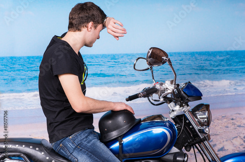 Man on Motorcycle Wiping Forehead at Beach
