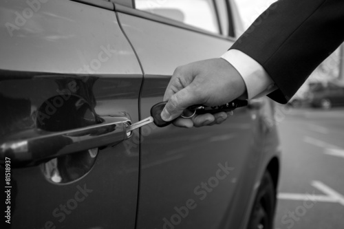 Black and white closeup of man inserting car key in the hole