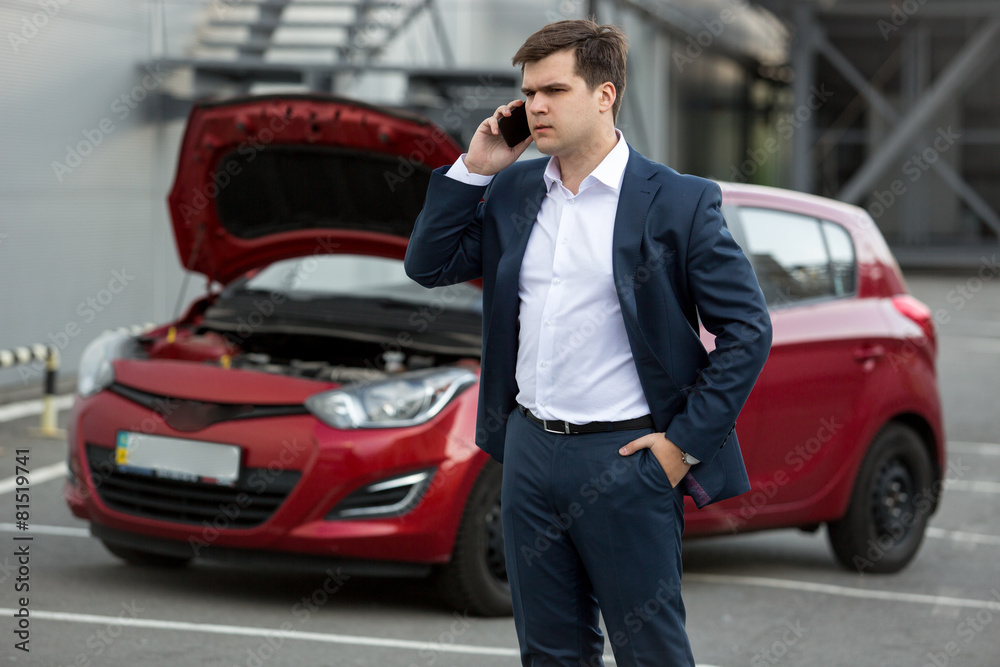 Portrait of man standing at broken car and calling repair servic Portrait of man standing at broken car and calling repair servic