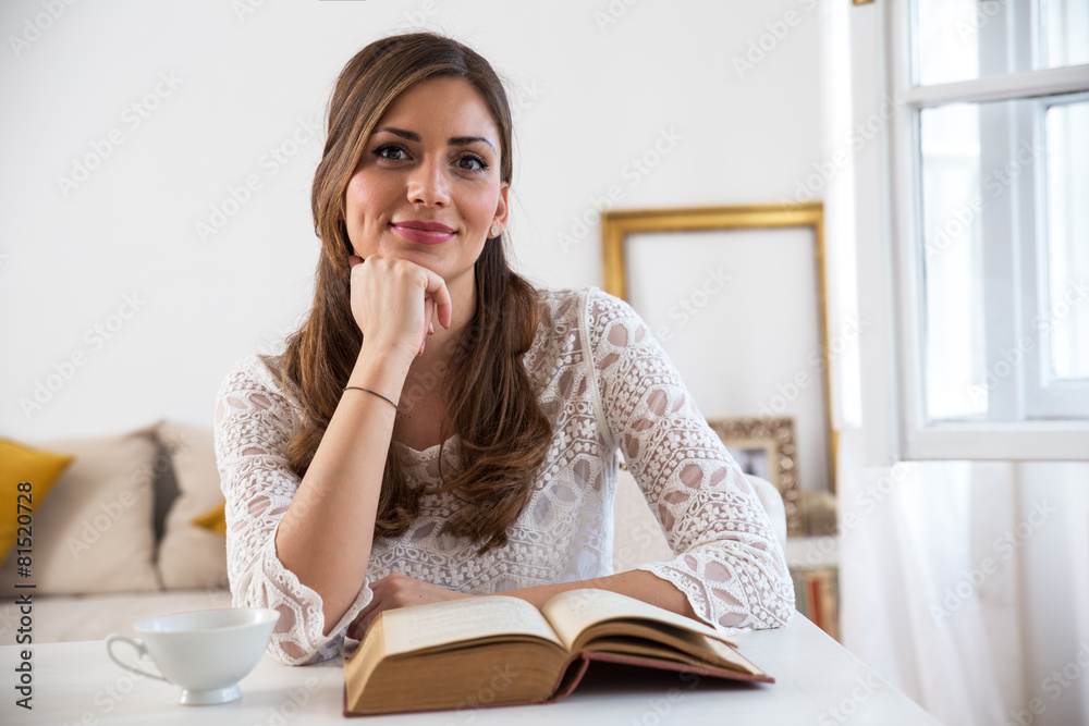 Charming woman sitting by wooden table and reading book Charming woman sitting by wooden table and reading book