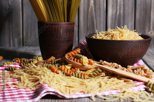 Different types of pasta on napkin on wooden background