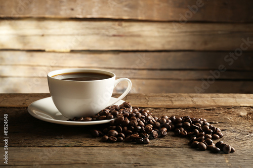 Cup of coffee with grains on wooden background