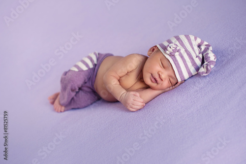 Smiling Baby Girl in a Sleeping Cap and Pants