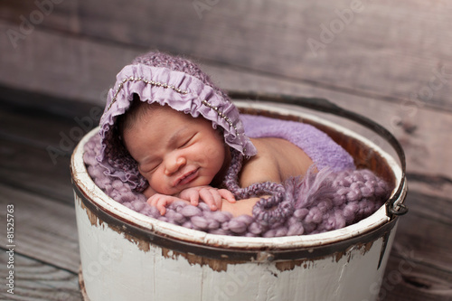Smiling Baby Girl with Lilac Bonnet Sleeping in a Bucket