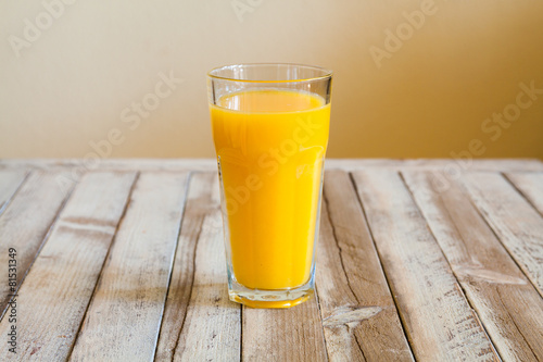 Glass of orange juice on white wooden background