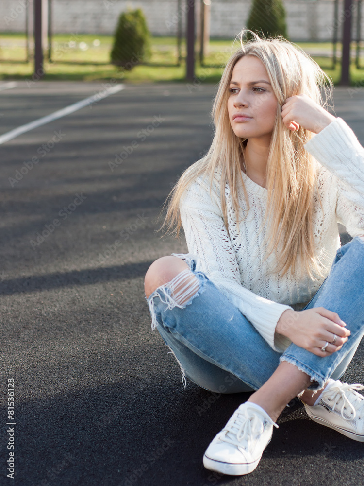 Young pretty fashionable blonde woman dressed in ripped jeans foto de Stock  | Adobe Stock