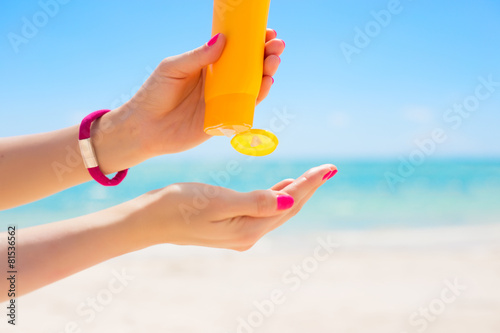 Woman pouring sunscreen in hand photo